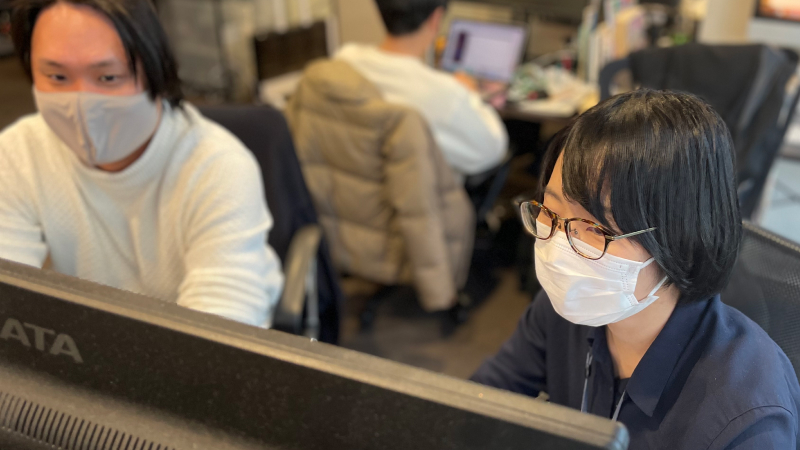 パソコンで仕事している濱崎七海と隣の白い服の男性